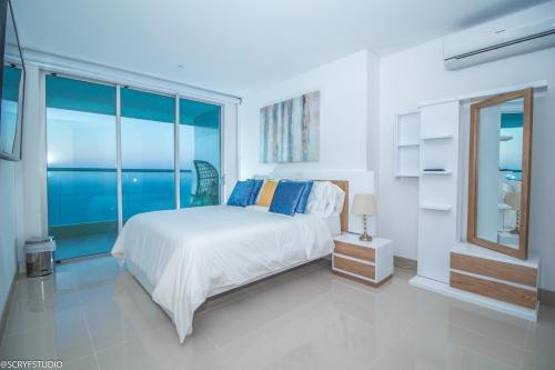 ein weißes Schlafzimmer mit einem Bett und einem großen Fenster in der Unterkunft Precioso apto de 1 habitación con vista extraordinaria en Bocagrande in Cartagena de Indias