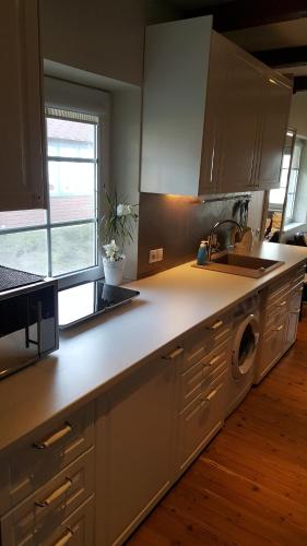 a kitchen with white cabinets and a sink and a dishwasher at Preila Kristina -1 in Neringa