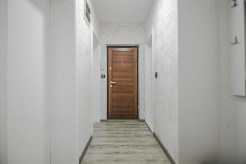 a corridor with a wooden door in a white hallway at Kristal Apartmani in Arandjelovac