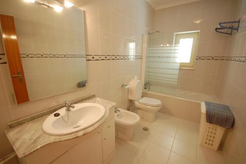 a bathroom with a sink and a toilet and a mirror at Apartamento Patel in Poço Partido