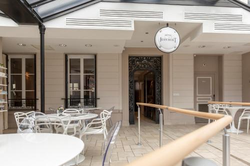 a restaurant with white tables and chairs and a clock at Hotel Jean Moët in Épernay