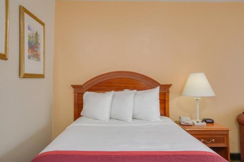 a hotel room with a bed with white pillows at Days Inn by Wyndham Asheville West in Candler
