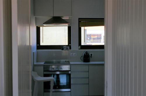 パレーデにあるBlue Apartment Parede Beach Houseのキッチン(コンロ、シンク付)、窓2つが備わります。