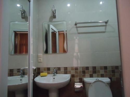 a bathroom with a sink and a toilet and mirrors at La'Rooms in Kutaisi