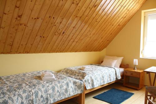 two beds in a room with a wooden ceiling at Kedvenc Vendégház in Miskolctapolca