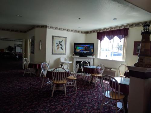 Lighthouse Inn في كريسنت سيتي: غرفة طعام بها طاولات وكراسي وتلفزيون