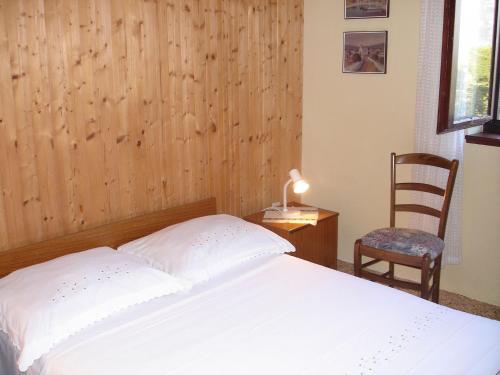 a bedroom with a white bed and a chair at Apartment Lucija in Korčula