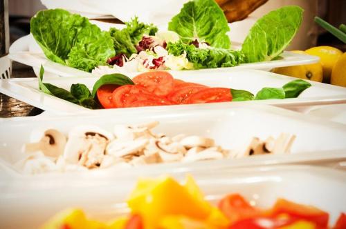 three plates of food on a table with lettuce and tomatoes at Landgasthof & Hotel Jagdhof in Stralsund