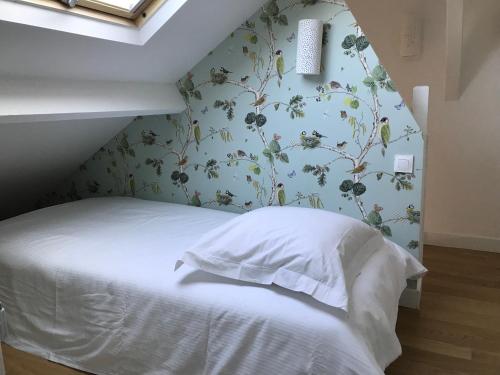 ein Schlafzimmer mit einem weißen Bett mit Blumentapete in der Unterkunft Deauville Triangle d OR in Deauville