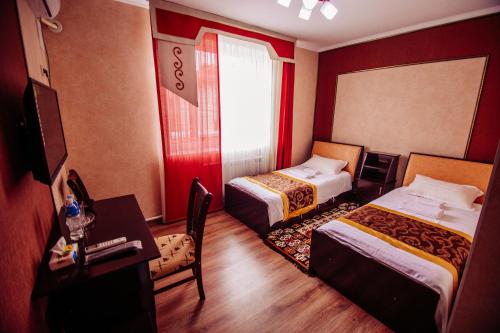 a hotel room with two beds and a desk at Asman Guest House in Osh