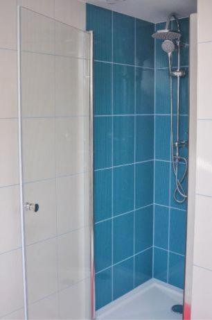 y baño con ducha de azulejos azules. en Nocleg w Małastowie, en Małastów