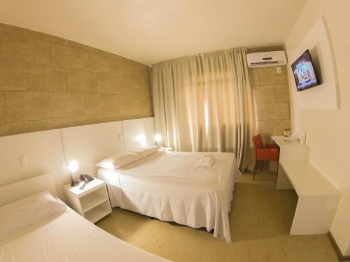 a hotel room with two beds and a window at Hotel São Marcos in São Marcos