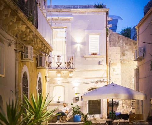a man sitting under an umbrella in an alley at Stay In Ortigia in Siracusa