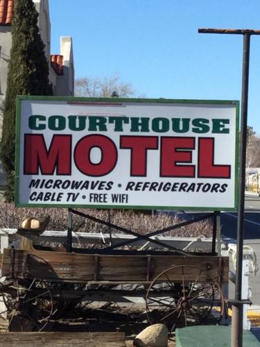 a sign for a courthouse motel with a bench at Independence Courthouse Motel in Independence