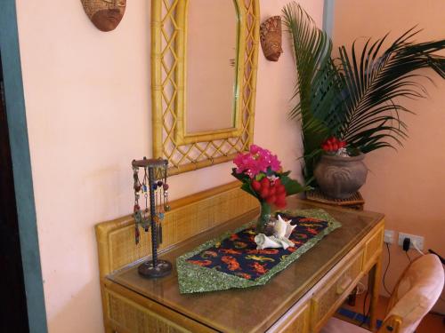 a table with a mirror and a vase with flowers at Reef View Pavilions - Villas & Condos in Lance aux Épines