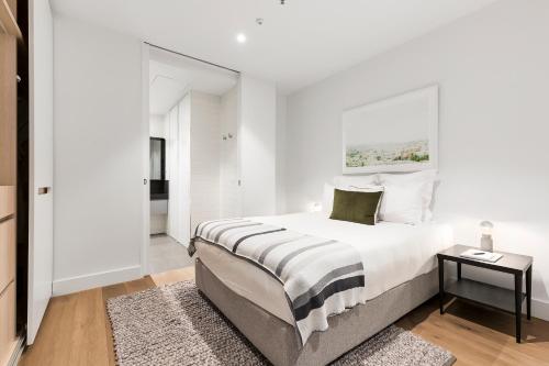 a white bedroom with a large bed and a window at Tyrian Albert Park Lake in Melbourne