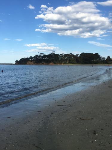 a beach with water and trees in the background at Aquarius Batehaven in Batemans Bay