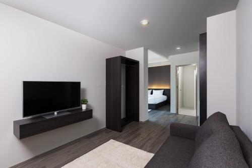 a living room with a couch and a flat screen tv at @S115 Residence in Samutprakarn