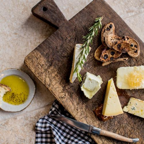 a cutting board with cheese and bread and a knife at The William Inglis Mgallery in Warwick Farm