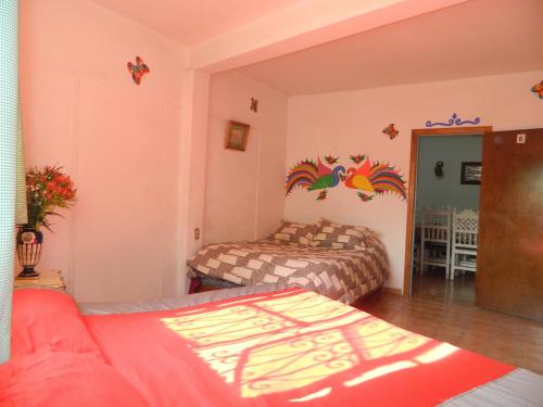 two beds in a room with pink walls at Posada Joan Sebastian in Taxco de Alarcón