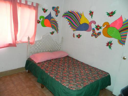 a bedroom with a bed with colorful birds on the wall at Posada Joan Sebastian in Taxco de Alarcón