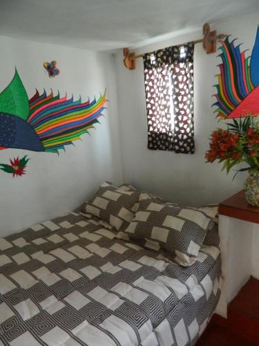 a bedroom with a bed in a room with art on the walls at Posada Joan Sebastian in Taxco de Alarcón