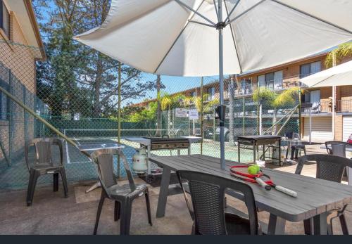 a patio area with tables, chairs and umbrellas at Aquarius Batehaven in Batemans Bay
