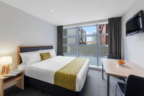 um quarto de hotel com uma cama e uma grande janela em Tetra Serviced Apartments by Castle em Auckland