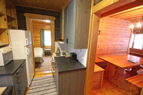 a kitchen with a refrigerator and a table in a cabin at Mäkelän Lomatuvat Bed and Breakfast in Hyytiälä