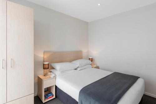 a bedroom with a large white bed with a night stand at Tetra Serviced Apartments by Castle in Auckland