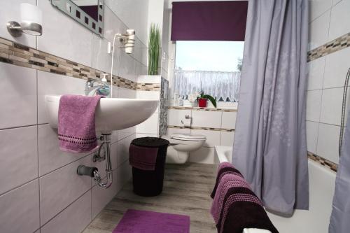 a bathroom with a sink and a toilet with purple towels at Ferienwohnung Zum alten Zollhaus in Bergen an der Dumme