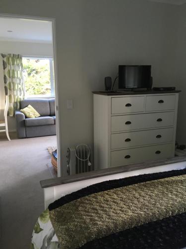 a living room with a dresser and a mirror at Incline Cottage in Upper Hutt
