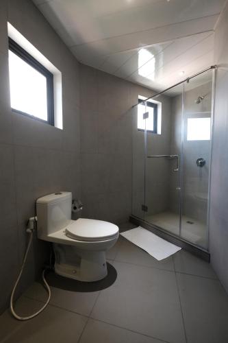 La salle de bains est pourvue de toilettes et d'une douche en verre. dans l'établissement U Hotels Makati, à Manille