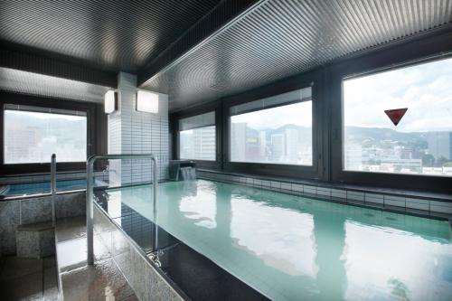 a large swimming pool in a building with windows at Hotel Nagano Avenue in Nagano
