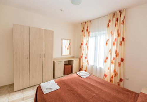 a bedroom with a bed with a red blanket and a window at Belle Air in Sunny Beach