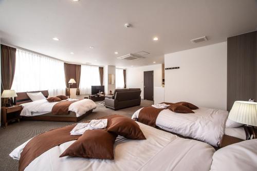 a hotel room with three beds and a chair at Condominium Stella Site in Hakodate