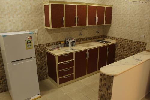 a kitchen with brown cabinets and a white refrigerator at AL Ibdaa Compound Furnished Apartments in Baish