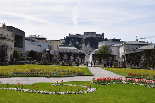 a park with flowers and a castle in the background at Atel Hotel Lasserhof in Salzburg