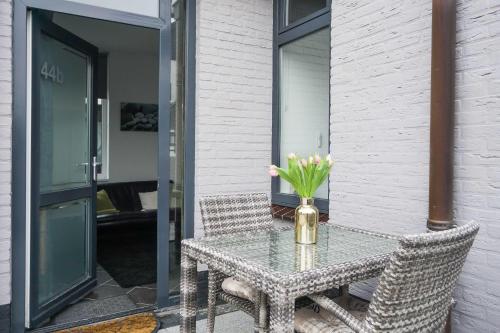 une table en verre avec un vase de fleurs sur elle dans l'établissement Strandzand, à Noordwijk aan Zee