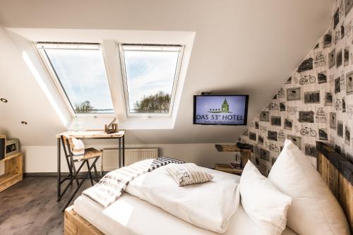 a room with a bed and a desk and two windows at Das 53°Hotel in Bad Zwischenahn