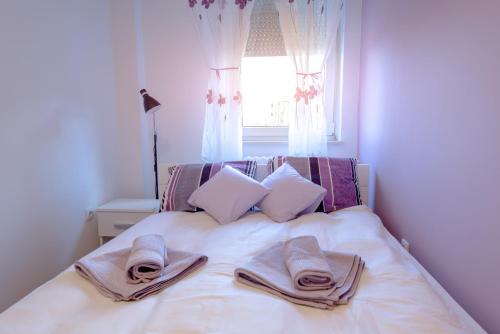 a white bed with towels on it with a window at Apartman Arte in Novi Sad