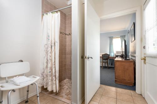 baño con ducha a ras de suelo junto a un escritorio en Wilshire Motel en Los Ángeles