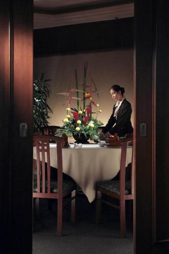 a woman sitting at a table with a vase of flowers at Cititel Penang in George Town