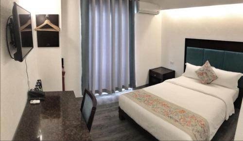 長灘島的住宿－長灘島埃爾普爾托酒店，一间卧室配有一张床、一张书桌和一个窗户。