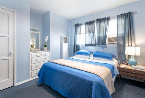a blue bedroom with a bed and a dresser at Wilshire Motel in Los Angeles