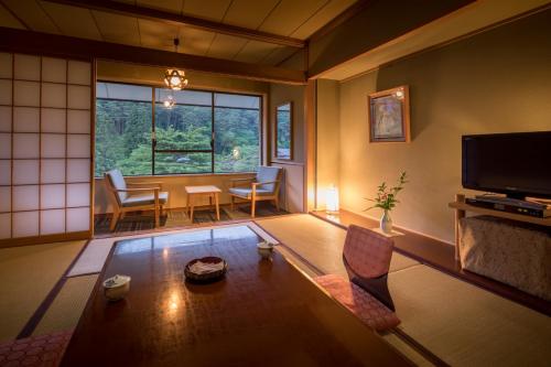 a living room with a table and a large window at Hotel Koyokan in Hanamaki