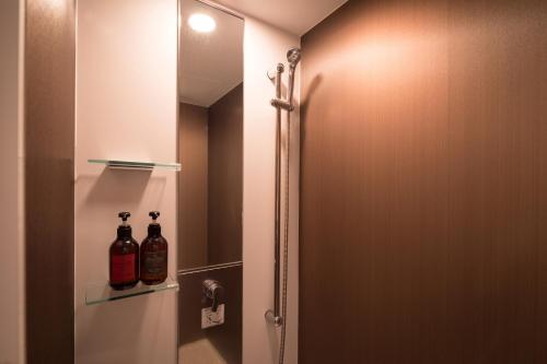 a bathroom with a shower with two bottles on a shelf at Hotel Koyokan in Hanamaki