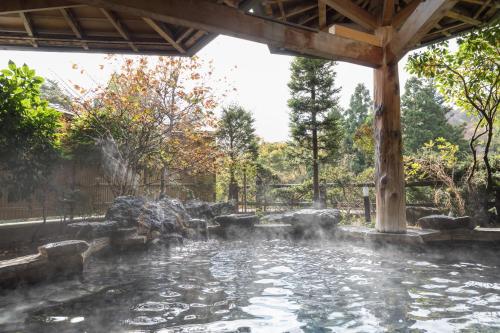 a pool of water in a garden with a gazebo at Hotel Koyokan in Hanamaki