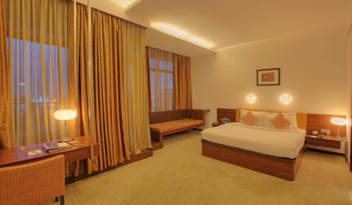 a hotel room with a bed and a desk and window at Hotel Parc Estique in Pune