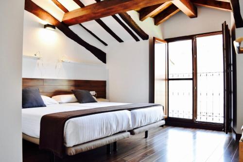 um quarto com uma cama grande e uma janela grande em Apartamentos Turísticos Rincones del Vino em Ezcaray